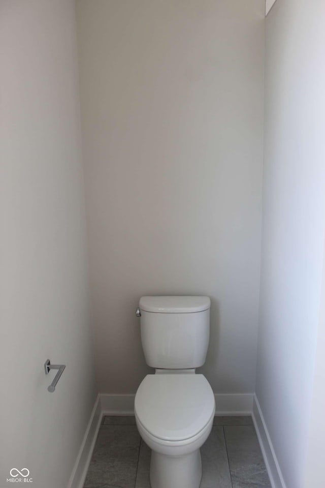 bathroom with baseboards, toilet, and tile patterned flooring