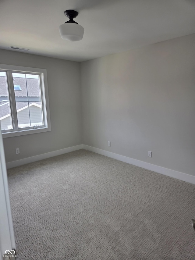 unfurnished room featuring baseboards, visible vents, and carpet