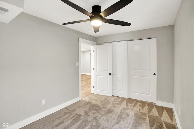 unfurnished bedroom featuring visible vents, a closet, carpet flooring, baseboards, and ceiling fan