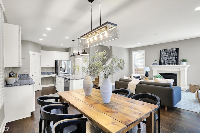 dining room with a glass covered fireplace, recessed lighting, and dark wood-style flooring