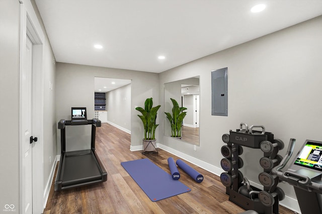 exercise room with electric panel, recessed lighting, baseboards, and wood finished floors