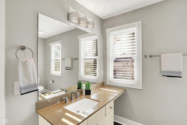 bathroom featuring vanity, toilet, and baseboards