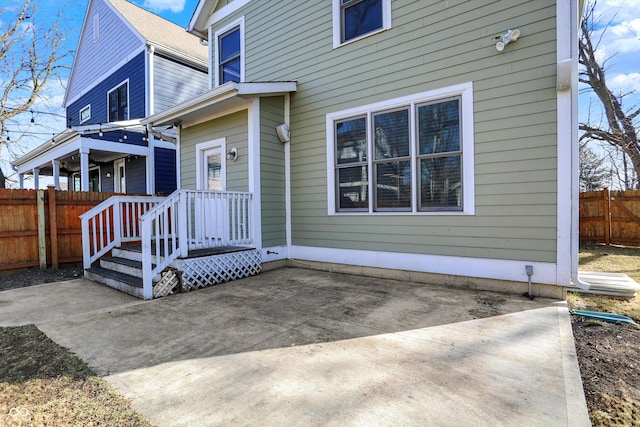 entrance to property featuring fence and a patio area