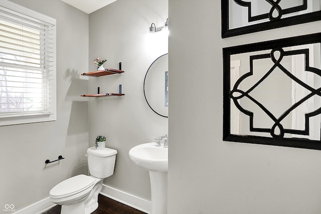 half bath with a sink, baseboards, toilet, and wood finished floors