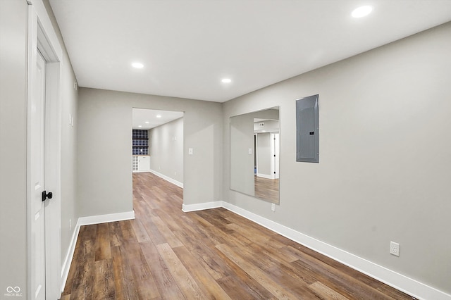 spare room featuring recessed lighting, electric panel, wood finished floors, and baseboards