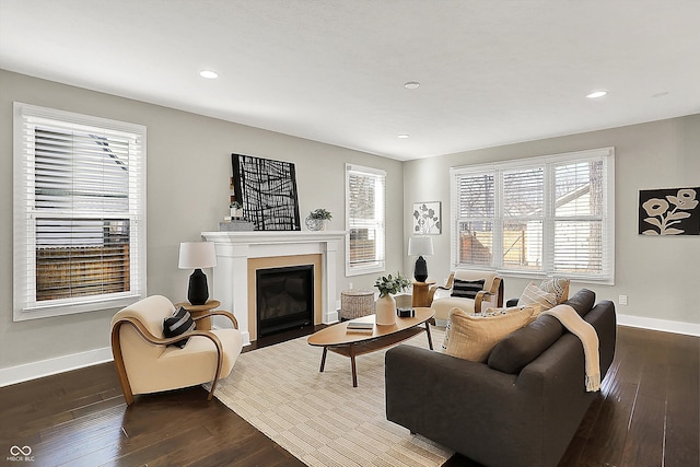 living room with recessed lighting, baseboards, a fireplace with flush hearth, and dark wood-type flooring