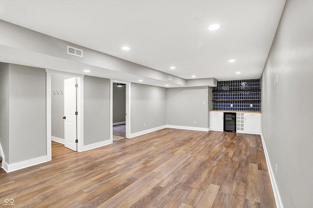 interior space featuring a bar, beverage cooler, visible vents, and light wood-type flooring