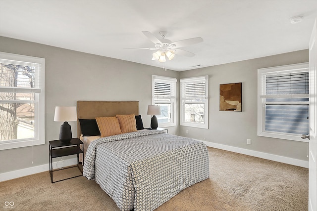 bedroom with multiple windows, light colored carpet, and baseboards