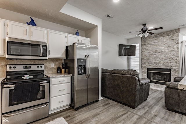 kitchen with tasteful backsplash, light wood-style flooring, appliances with stainless steel finishes, open floor plan, and white cabinetry