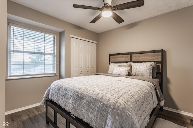 bedroom with a closet, dark wood-style flooring, ceiling fan, and baseboards