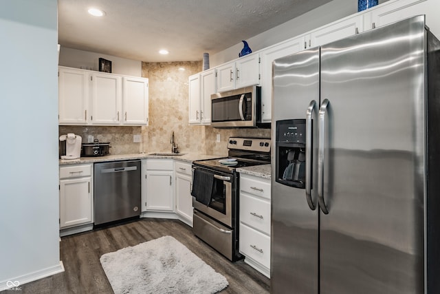 kitchen with appliances with stainless steel finishes, backsplash, a sink, and white cabinetry