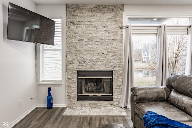 unfurnished living room with a fireplace with flush hearth, baseboards, and wood finished floors