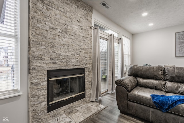 living area featuring a fireplace, recessed lighting, visible vents, a textured ceiling, and wood finished floors