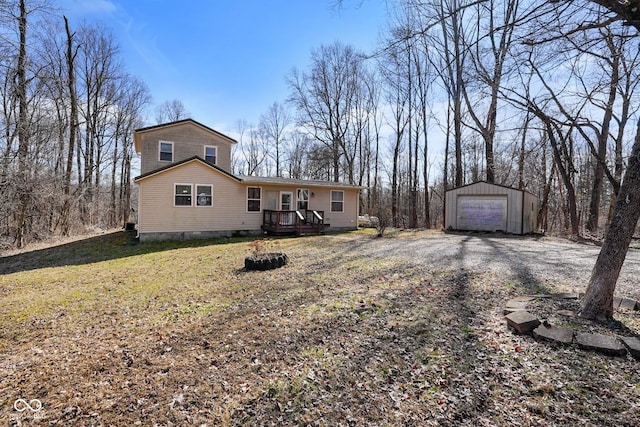 view of front of property featuring driveway, an outdoor structure, a detached garage, and a front yard