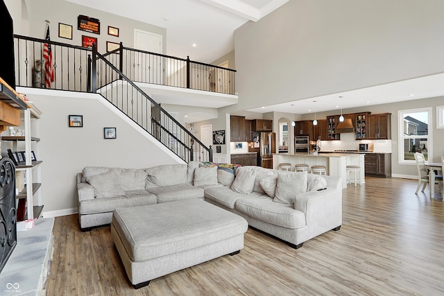 living room with stairs, recessed lighting, light wood-type flooring, and baseboards