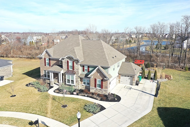 view of front facade featuring a front yard, stone siding, driveway, and a residential view