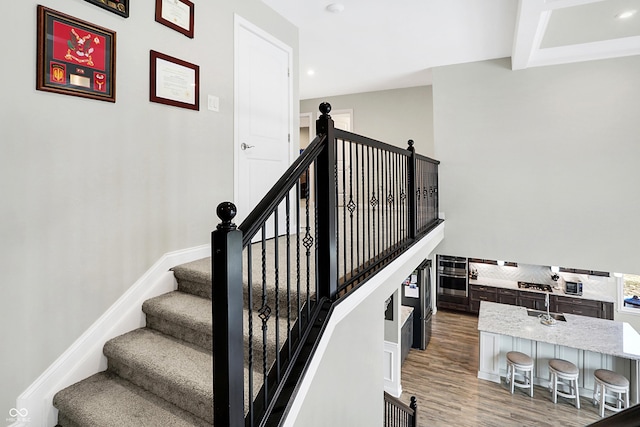 stairs with baseboards, wood finished floors, and recessed lighting