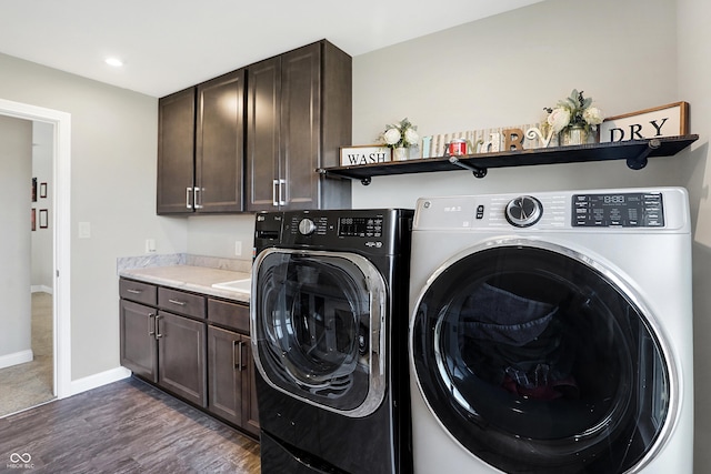 laundry room featuring dark wood-style flooring, washer and clothes dryer, cabinet space, and baseboards