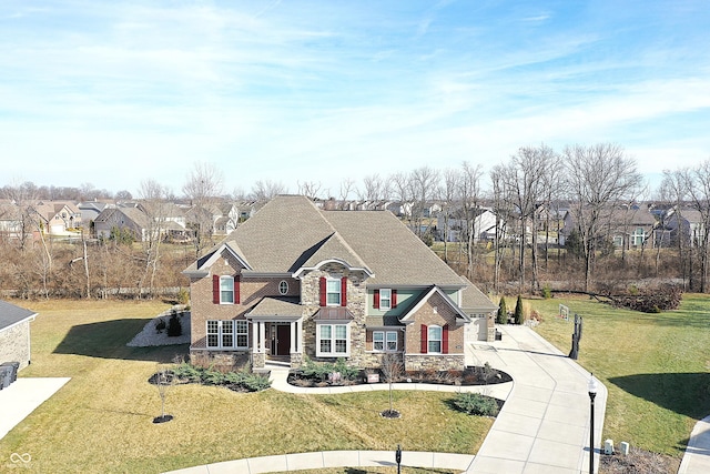 traditional-style home featuring stone siding, a residential view, a front lawn, and concrete driveway