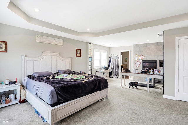 carpeted bedroom with a tile fireplace, recessed lighting, visible vents, baseboards, and a raised ceiling