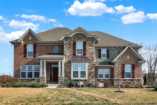 view of front of home featuring stone siding, a front lawn, and roof with shingles