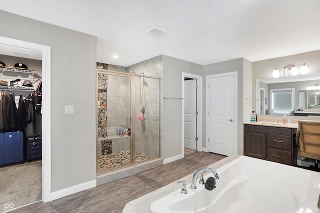 full bathroom with a garden tub, vanity, visible vents, a spacious closet, and a stall shower