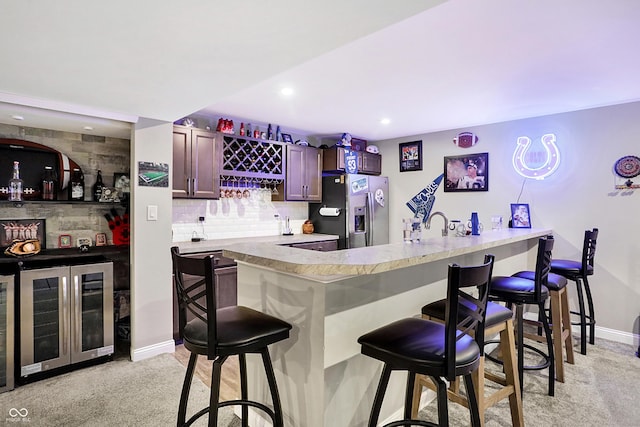 bar featuring wine cooler, stainless steel refrigerator with ice dispenser, and indoor wet bar