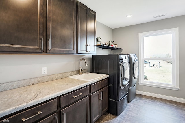 clothes washing area featuring a sink, visible vents, baseboards, washer and dryer, and cabinet space