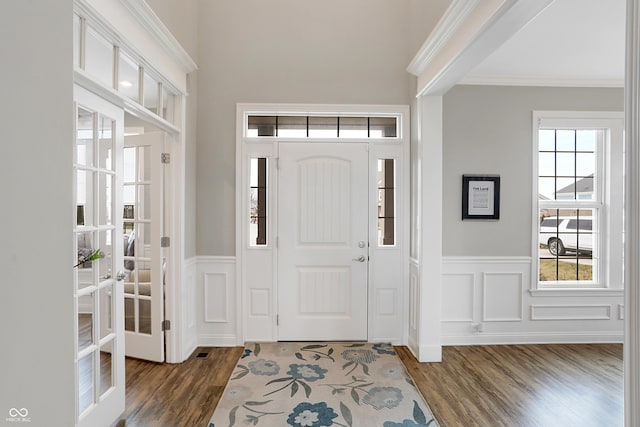 entryway featuring ornamental molding, wood finished floors, a wealth of natural light, and a decorative wall