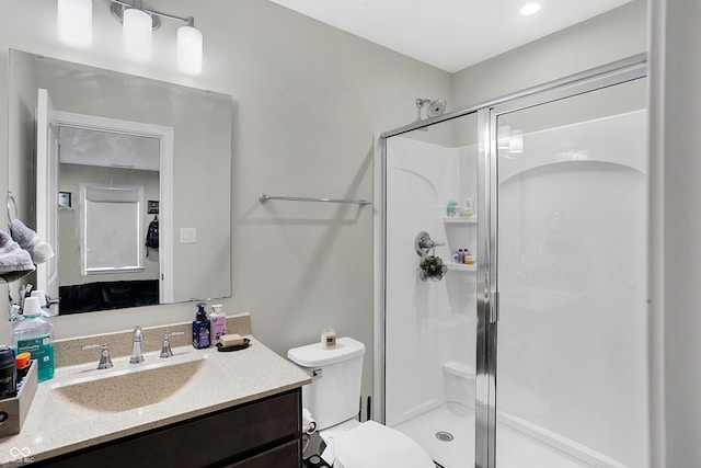 bathroom featuring toilet, a stall shower, and vanity