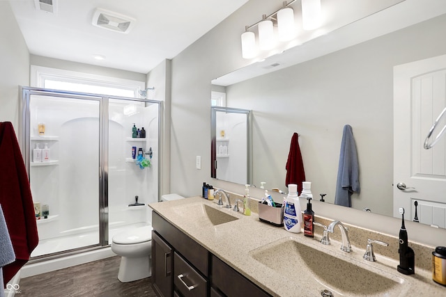 full bathroom featuring toilet, a shower stall, visible vents, and a sink