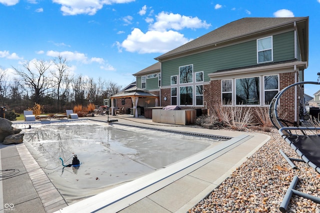 exterior space with brick siding, a patio, a hot tub, and a gazebo