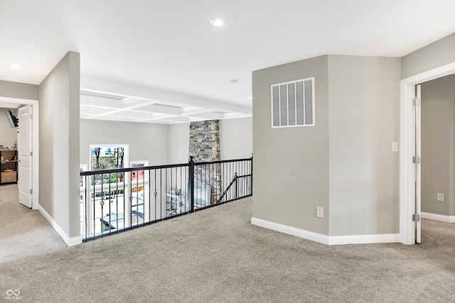 hall with carpet, visible vents, and baseboards