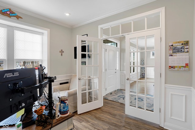 interior space featuring french doors, a wainscoted wall, crown molding, and wood finished floors