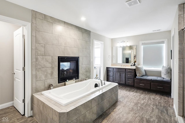 bathroom featuring visible vents, toilet, wood finished floors, a garden tub, and vanity