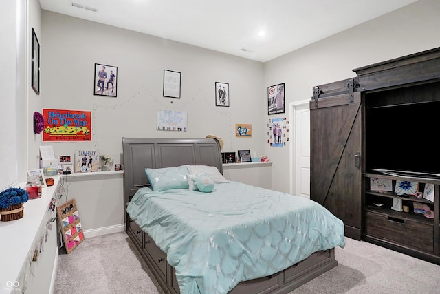 bedroom with baseboards, a barn door, visible vents, and light colored carpet