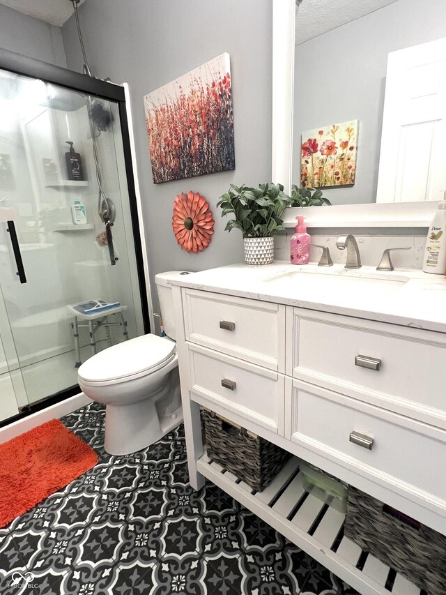 bathroom featuring a shower stall, toilet, and vanity