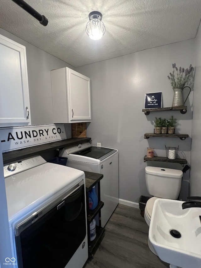 washroom featuring independent washer and dryer, a textured ceiling, baseboards, and dark wood-style flooring