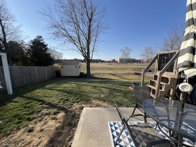 view of yard featuring a fenced backyard, a shed, an outdoor structure, outdoor dining area, and a patio area