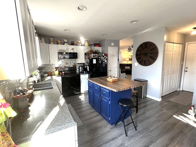 kitchen with a kitchen bar, decorative backsplash, white cabinets, black appliances, and blue cabinets