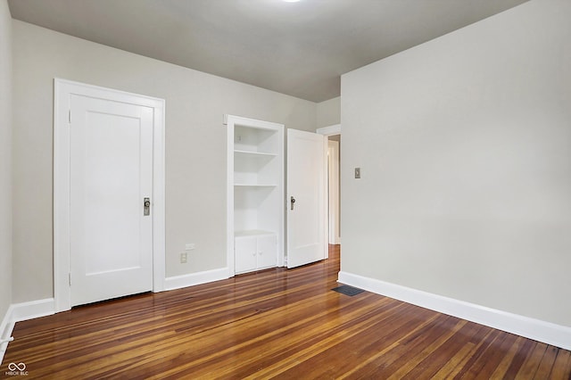 unfurnished bedroom featuring hardwood / wood-style flooring, visible vents, and baseboards