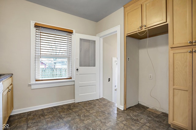 interior space featuring stone finish flooring, light brown cabinets, and baseboards