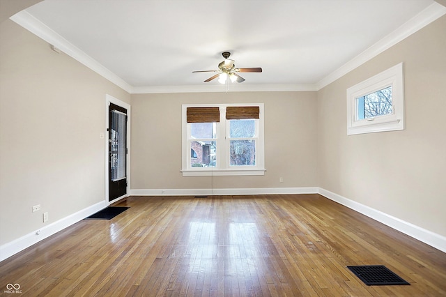 spare room featuring crown molding, visible vents, a ceiling fan, baseboards, and hardwood / wood-style flooring