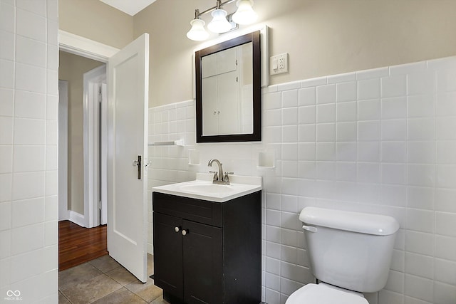 bathroom with toilet, vanity, tile patterned flooring, and tile walls