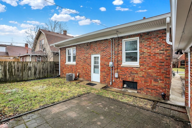 back of house with central AC unit, brick siding, fence, a yard, and a patio area