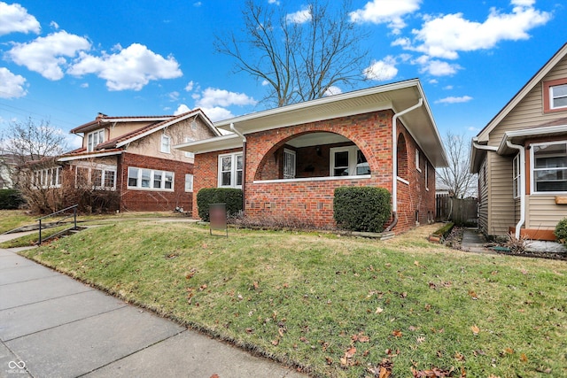 view of front of house with brick siding, a front yard, and fence