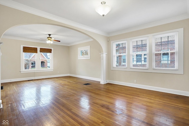 empty room with arched walkways, hardwood / wood-style flooring, visible vents, and baseboards