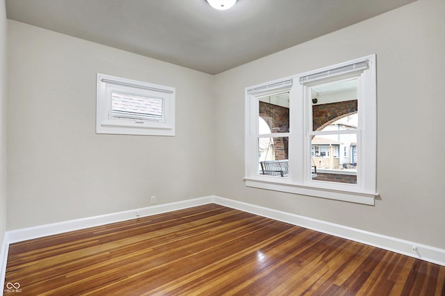 empty room with dark wood-type flooring and baseboards