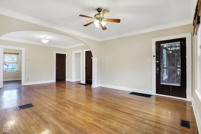 interior space with arched walkways, visible vents, baseboards, and hardwood / wood-style flooring