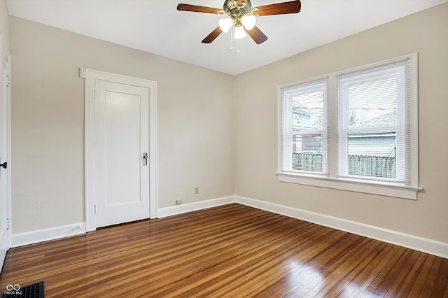 unfurnished room with a ceiling fan, visible vents, hardwood / wood-style floors, and baseboards